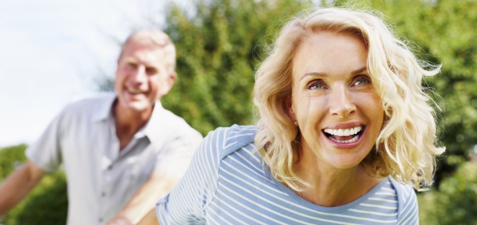 Smiling man and woman walking outdoors after restorative dentistry in Jackson