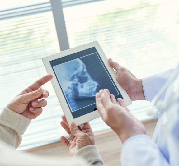 Two dentists looking at jaw x rays on tablet